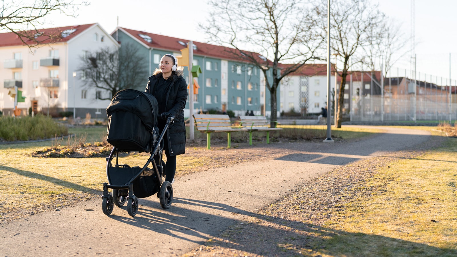 kvinna går med barnvagn i bostadsområde