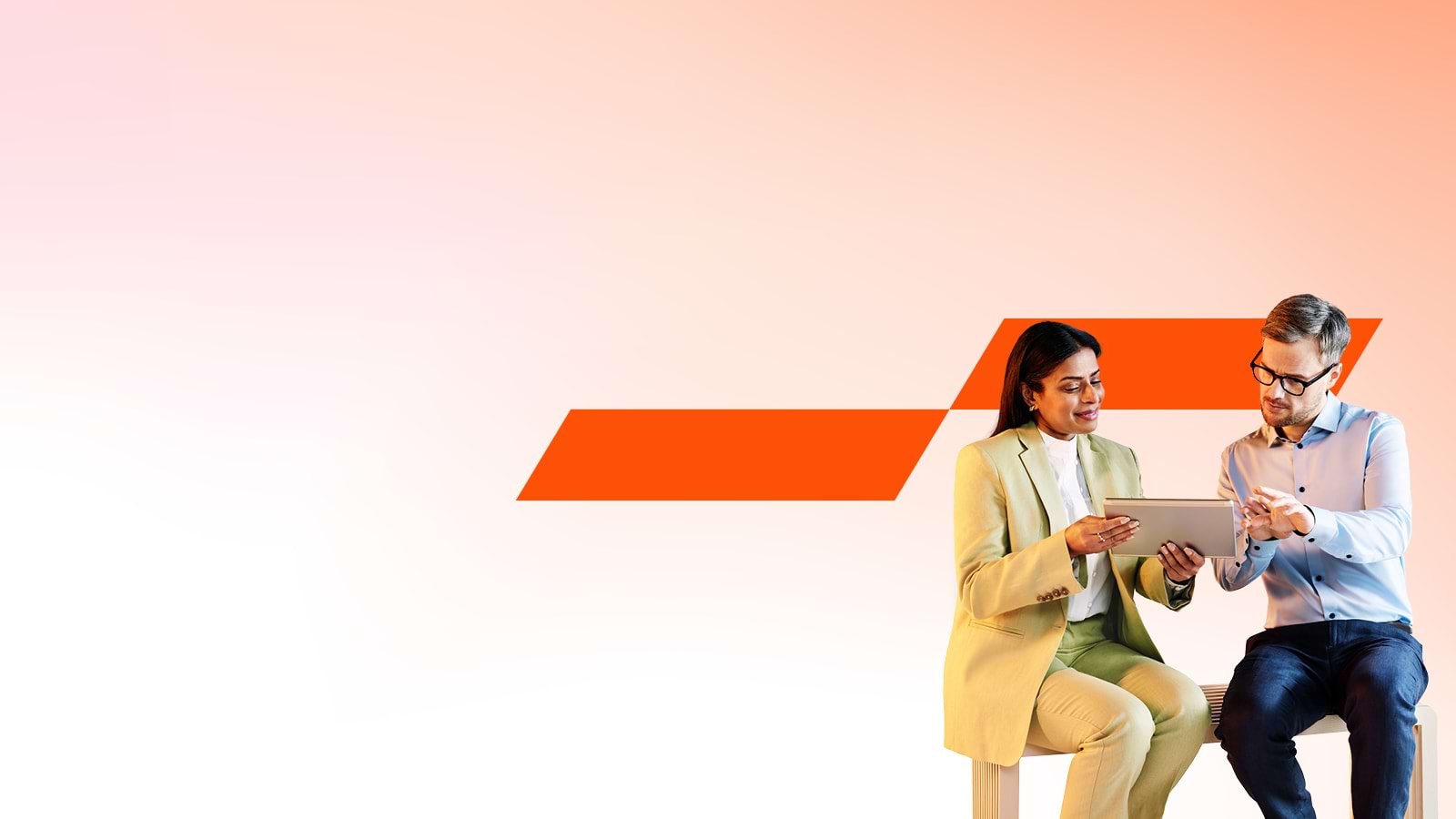 Två kollegor, en kvinna och en man, sitter och tittar på en surfplatta.